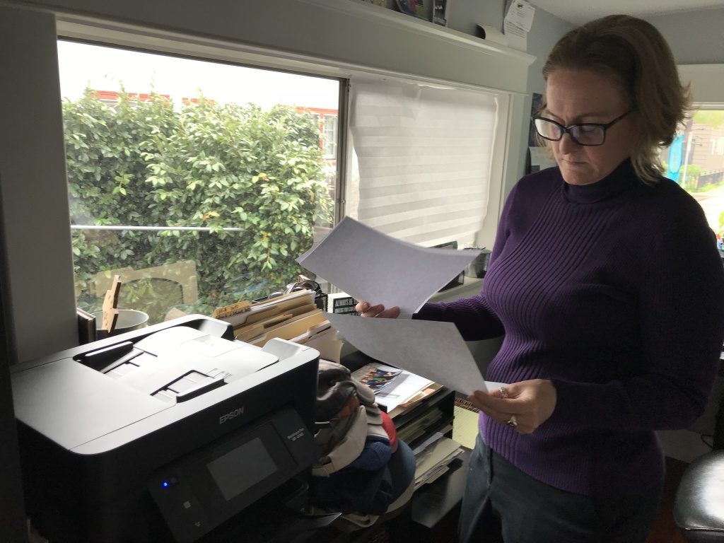 Heather Altman looks through old health insurance bills in her Long Beach home office, Jan. 16, 2019 (David Wagner/KPCC)